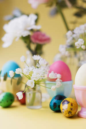 Easter eggs and flowers on a yellow background. Easter background with pastel colors details. spring holiday conceptの写真素材