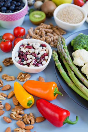 Balanced diet food background. Fresh vegatables, fruits, cereals, seeds and nuts on a blue...