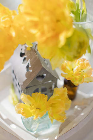 Yellow flower tulip in vase on a wooden tray at windowsill. Flowers, metal vintage house decoration...