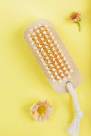 Hair brush, anti-cellulite brush, nail brush with orange flower on a yellow background. Eco...