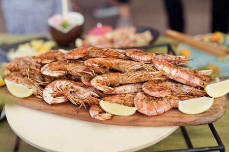 Grilled shrimp with lemon on a wooden tray. outdoor party food conceptの写真素材