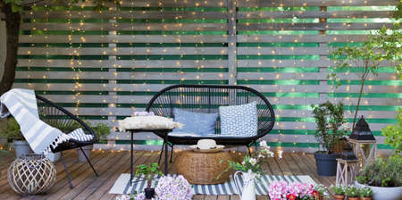 Lounge garden furniture at backyard. Black sofa and chair with pillows and blanket at the garden...