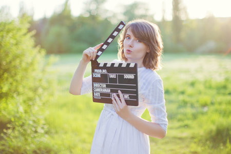 Beautiful caucasian woman in white dress walks in spring blossom gardenの写真素材