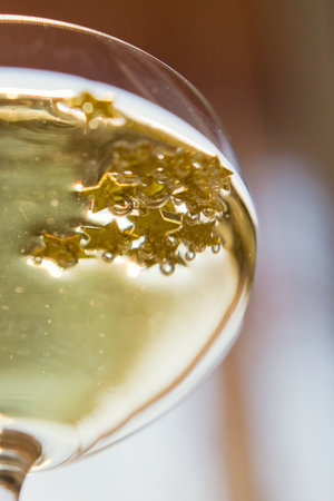 Glass of champagne with golden stars confetti on the silver tray. New year party conceptの写真素材
