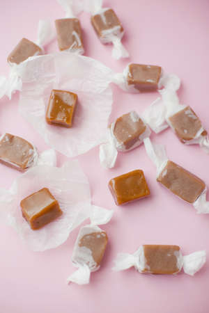 Caramel candy fudge in paper wrapping on a pink backgroundの写真素材