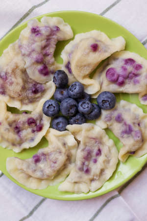 Traditional ukrainian dish varenyky with blueberries on a green plateの写真素材