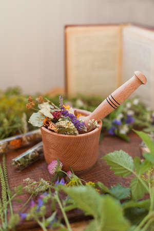 Homeopathy and herbal medicine concept. Wooden mortar and pestle with dry herbs, wildflowers, chalkboard and glass bottles on a wooden backgroundの写真素材