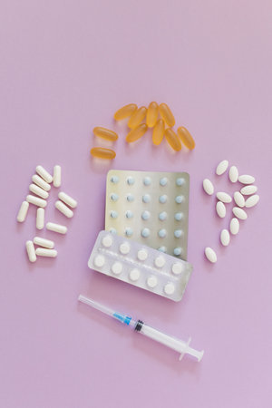 Assorted pills and plastic syringe on the pink background with copy spaceの写真素材