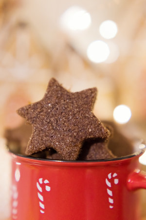Christmas star shaped gingerbread cookies in a red mug on a christmas lights background