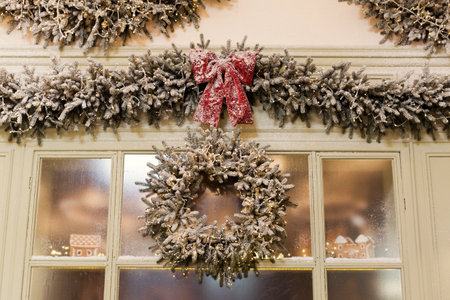 Decorated Christmas garland with red bow and round wreath on a showcase of bakeryの写真素材