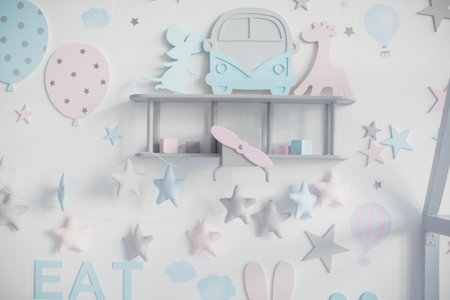 White wall with hanging pink and blue wooden decorations. Kids room interior concept. Festive decorations on childs or baby shower partyの写真素材