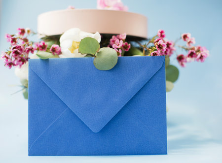 Blue envelope and pink gift box with bouquet on a blue backgroundの写真素材