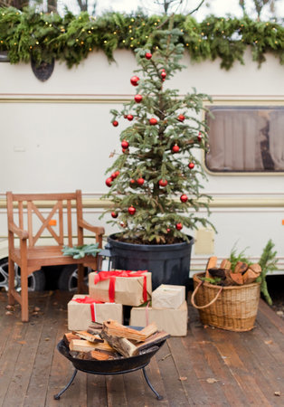 Vintage old travel trailer with Christmas decorations, Christmas tree, chair and Christmas lights. Cozy home, camping before Christmas holidays.の写真素材