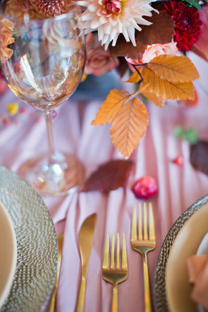 Beautiful table setting with autumn flowers, orange and pink napkins and burning candles. Autumn...