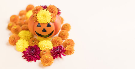 Banner with Halloween pumpkin and orange chrysanthemums on a beige background with copy space. Halloween concept backgroundの写真素材