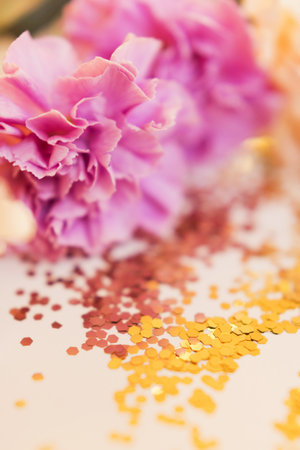 Pink and beige dianthus flowers and golden glitter confetti on a white background close upの写真素材