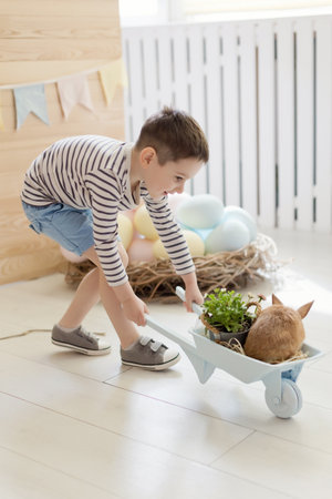 Caucasian boy with cute bunny on a light kitchen interior with Easter decorations