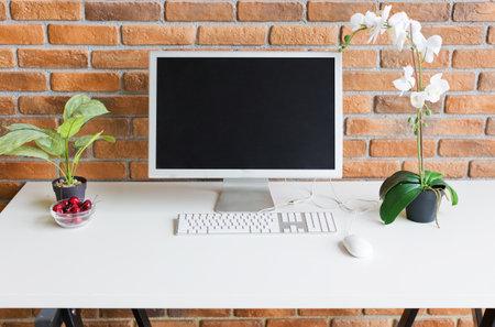 Workspace with computer on the table near brown brick wall, copy space