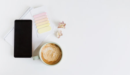 Flat lay with smartphone, cup with coffee and sticky  on a white background, copy spaceの写真素材