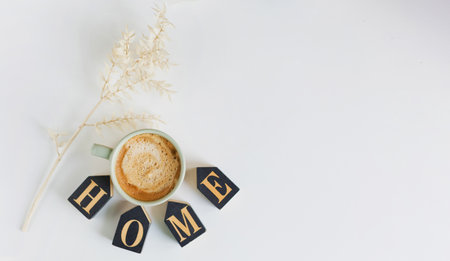 Cup with coffee, black wooden home decoration and white dry flower on a white table background, copy spaceの写真素材