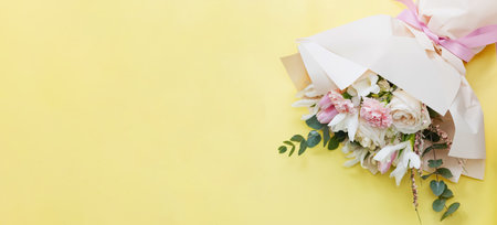Beautiful bouquet with roses, carnations, iris and eucalyptus on a yellow background, copy space. Mothers day, 8 march, holiday gift conceptの写真素材