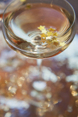 Glass of champagne with golden stars confetti on the silver tray. New year party conceptの写真素材