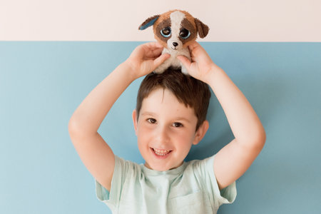 Caucasian boy with stuffed toy on a blue background with copy spaceの写真素材