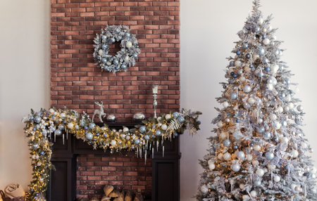 Living room with black fireplace and Christmas tree with silver and blue decorations and lights near brown brick wallの写真素材