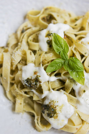 Homemade tagliatelle pasta with pesto sauce and stracciatella di bufala cheese on a plateの写真素材