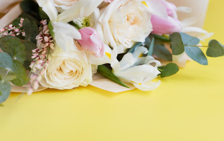 Beautiful bouquet with roses, carnations, iris and eucalyptus on a yellow background, copy space. Mothers day, 8 march, holiday gift conceptの写真素材