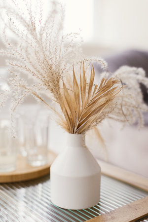 Dry flowers in white vase on a table at bright interiorの写真素材