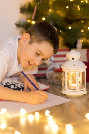 Boy lying near Christmas tree and writing letter to Santa Clausの写真素材