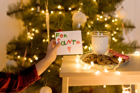 Milk, cookies for Santa Claus and letter near Christmas tree