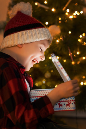 Boy in knit hat open Christmas gift with magic light insideの写真素材