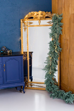 Vintage golden mirror decorated Christmas garland and lights on a background of blue wallの写真素材