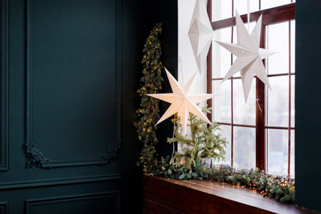 Dark interior with Christmas paper stars hanging on a windowの写真素材