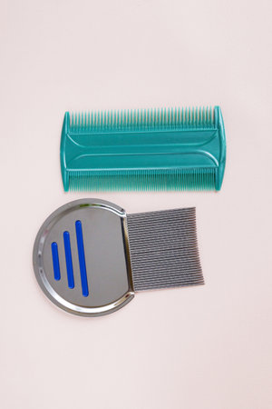 Metal and plastic lice combs on a pink background, copy spaceの写真素材