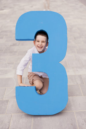 Caucasian boy and big blue number 3, third grade
