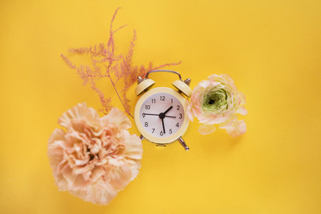 Yellow clock and flowers on a yellow background, copy spaceの写真素材