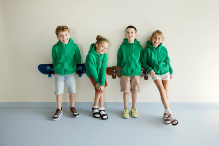 Kids in green hoodie school uniform near white wall background, copy space