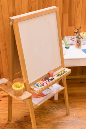 Wooden easel with paints and brushes for creative artworkの写真素材