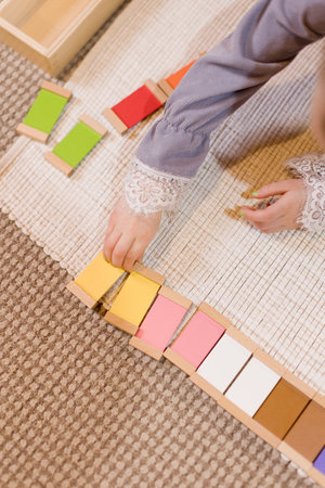 Child sorting colorful wooden blocks in a Montessori learning activityの写真素材