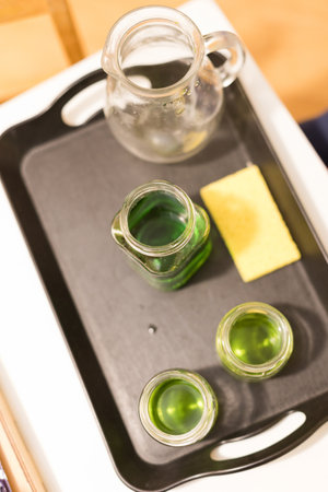Glass jars with green liquid on a tray, Montessori activityの写真素材