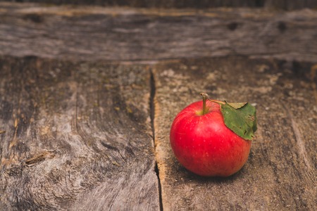 one red sweet apple with leaf on old wood backgroundの写真素材
