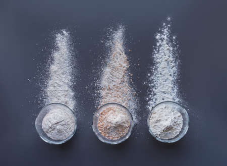 flours for bread making in glass cups: rye, wholegrain wheat, plain or all-purpose or strong flour arranged on a grey backgroundの写真素材