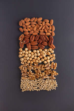 a pattern with almond, pine, pecan nuts, walnuts, hazelnuts on a grey tableの写真素材