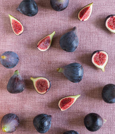 fresh cut and whole figs lying on pink textured background