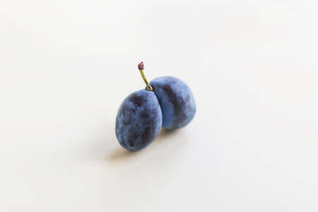 Ugly organic blue double plums heart-shaped on a white background. The ugly produce trend is the sale of imperfect-looking produce.の写真素材