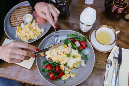 brunch or breakfast set up at a restaurant: 2 plates with sandwiches with avocado, eggs, salad,...