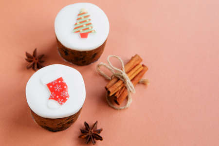 mini Christmas cakes on pink peach background, cinnamon and anise stars as eco decoration